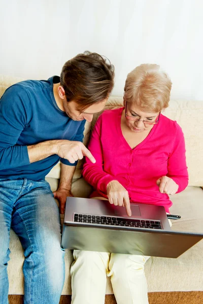 Mor och son sitter i soffan och tittar på något på laptop — Stockfoto