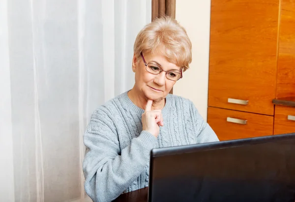 Sonrisa senior sentado en la mesa y el uso de ordenador portátil — Foto de Stock