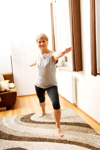 Senior vrouw doet yoga in de woonkamer — Stockfoto