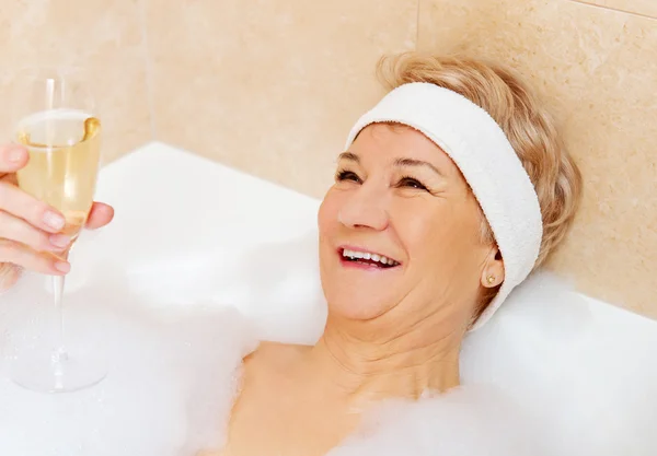 Femme âgée se détendre dans le bain avec une coupe de champagne — Photo