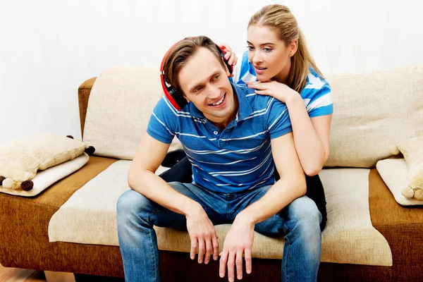 Casal relaxante no sofá, homem ouvindo música mulher abraçando-o — Fotografia de Stock