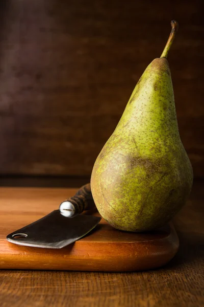 Pear and chopper on wooden cutting board — Stock Photo, Image