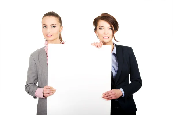 Two businesswomen carrying a big white board. — Stock Photo, Image