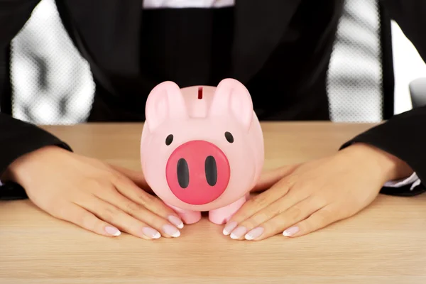 Geschäftsfrau mit Sparschwein hinter dem Schreibtisch — Stockfoto