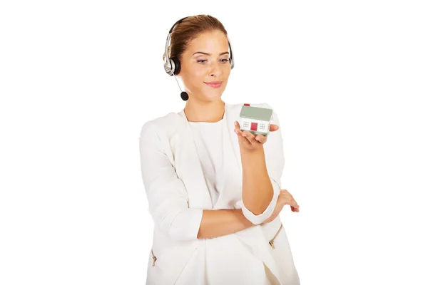 Young businesswoman in headset holds house model — Stock Photo, Image