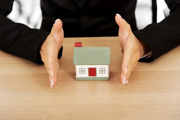 Businesswoman with small house behind the desk — Stock Photo, Image