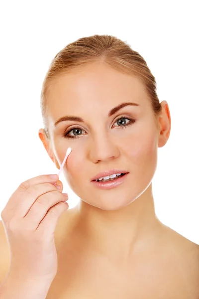 Young woman removing eye makeup with cotton swab — Stock Photo, Image