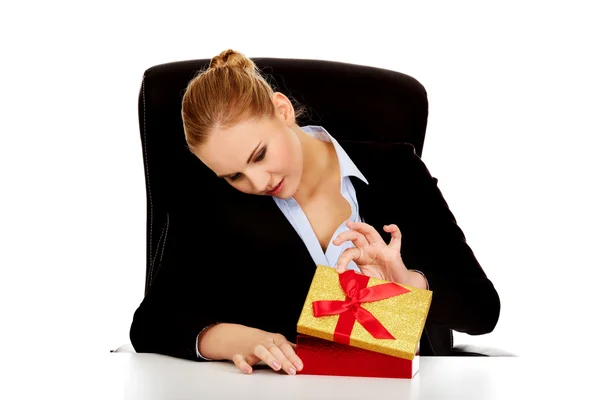 Посмішка бізнес жінка відкриває подарункову коробку за столом — стокове фото