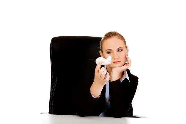 Business woman sitting behind the desk and holding a toy plane — Stock Photo, Image