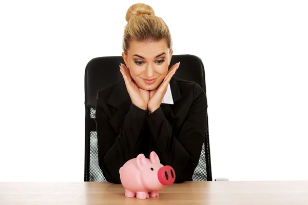 Geschäftsfrau mit Sparschwein hinter dem Schreibtisch — Stockfoto