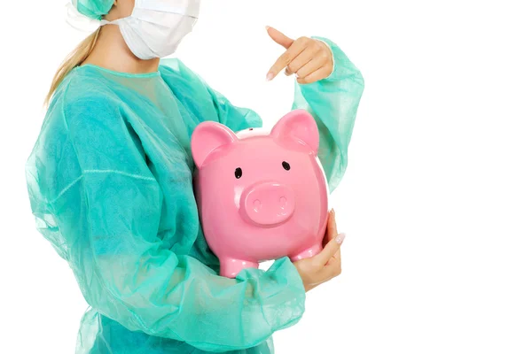 Female surgeon doctor holding piggy bank — Stock Photo, Image