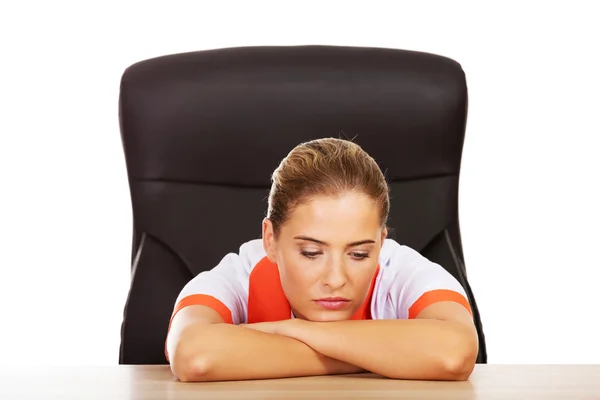 Tired young female doctoror nurse sitting behind the desk — Stock Photo, Image