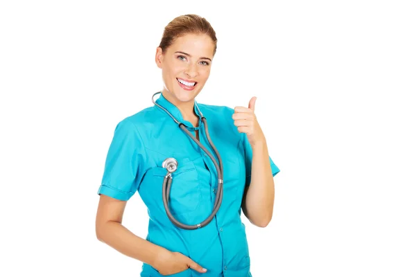 年轻的女医生或有隐窝的护士伸出大拇指 — 图库照片