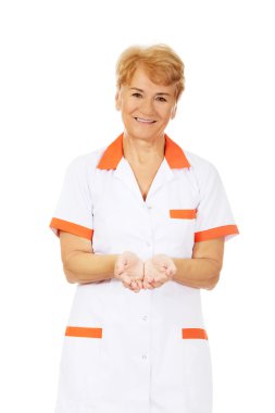 Yaşlı kadın doktor ya da hemşire avuçlarında bir şey sunarken gülümse.