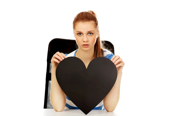 Worried teenage woman holding black paper heart — Stock Photo, Image