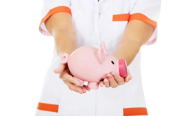 Sorria idosa médica ou enfermeira segurando piggybank — Fotografia de Stock