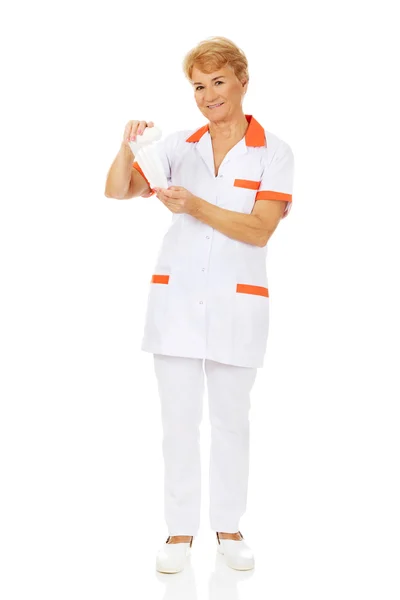 Sorria idosa médica ou enfermeira detém bandagem — Fotografia de Stock