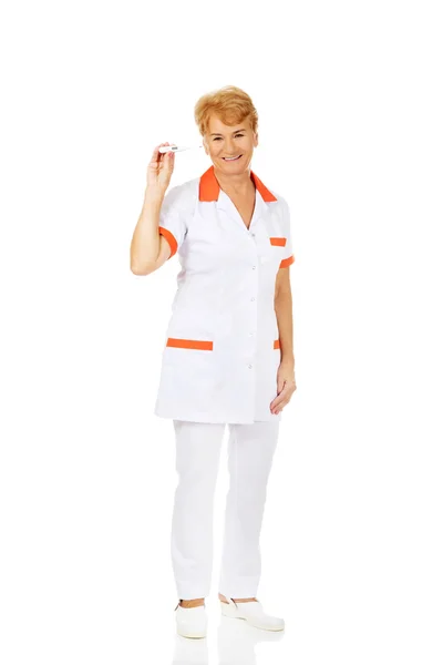 Sorria idosa médica ou enfermeira segurando termômetro — Fotografia de Stock