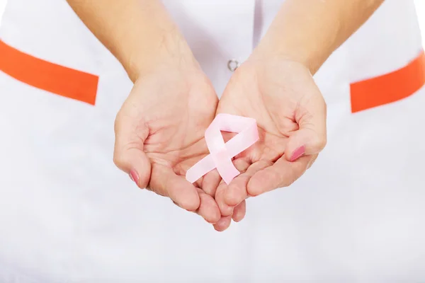 Elderly female doctor or nurse holds pink breast cancer awareness ribbon — Stock Photo, Image