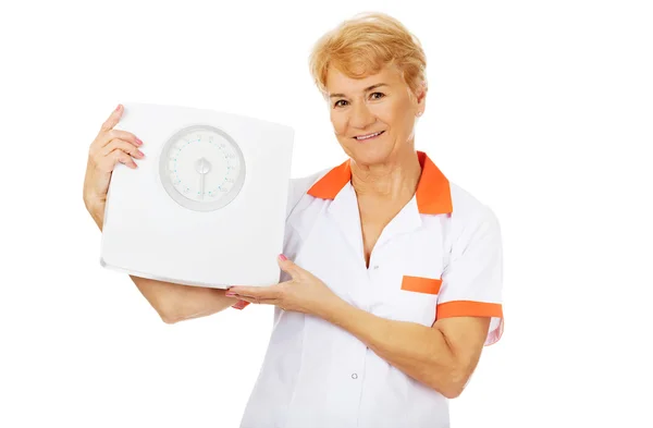 Посмішка літня жінка-лікар або медсестра тримає вагу — стокове фото