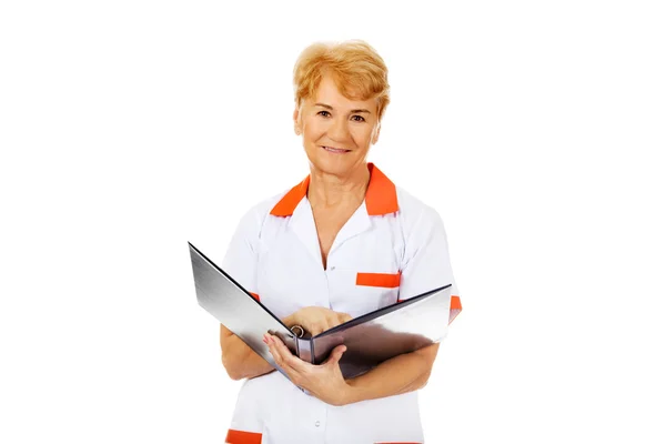노인 여성 의사 또는 간호사가 보유 하 고 블랙 바인더 및 읽기 — 스톡 사진