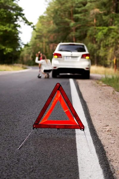 Triângulo de aviso vermelho e carro quebrado no meio de forrest — Fotografia de Stock