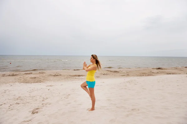 ビーチでのヨガの練習を作る若い女性 — ストック写真