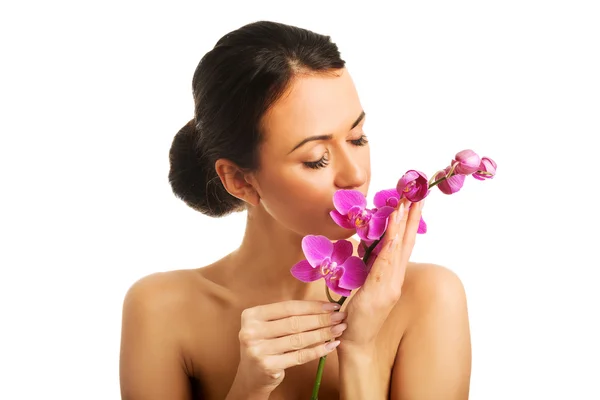 Женщина топлесс с фиолетовой ветвью орхидеи — стоковое фото