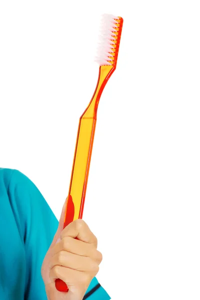 Молодая женщина-дантист или медсестра с огромной зубной щеткой — стоковое фото