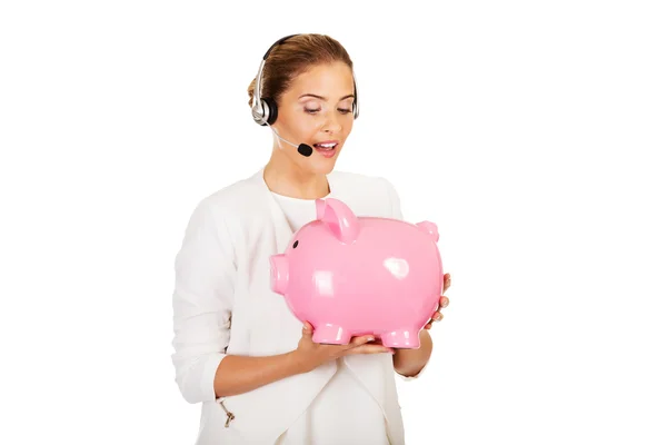 Jovem empresária em headset segurando piggybank — Fotografia de Stock