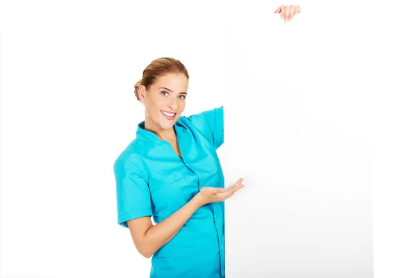 Jovem médica ou enfermeira segurando banner vazio — Fotografia de Stock