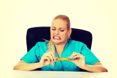 Şok ve korkmuş kadın hemşire ya da doktor arkasında oturan Resepsiyon ve paket hap holding