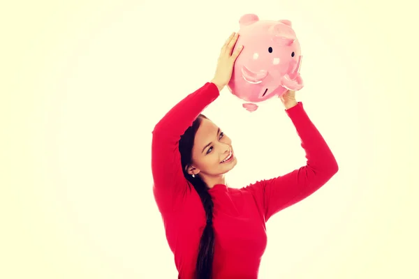 Glückliche junge Frau schüttelt Sparschwein — Stockfoto