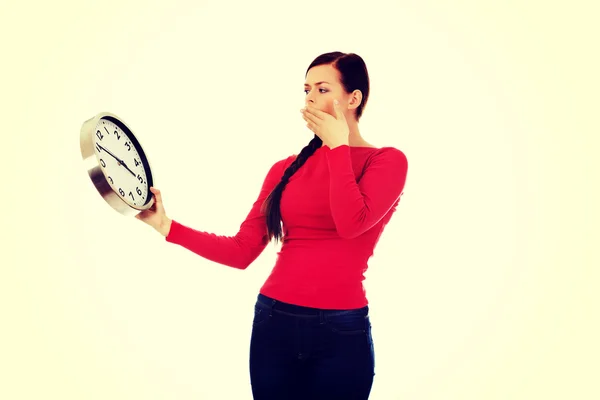 Young yawning woman holding a clock — Stock Photo, Image