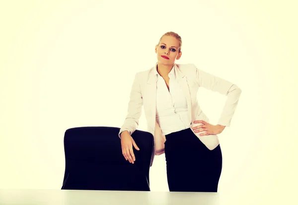 Jeune femme aux gros seins debout derrière le bureau leanig sur fauteuil — Photo