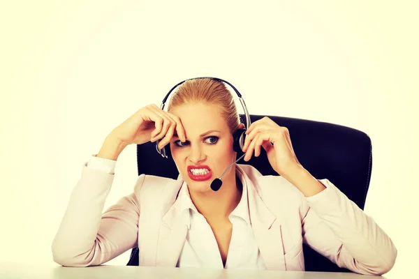 Mujer joven operador de línea de ayuda está tratando de escuchar algo a través de unos auriculares —  Fotos de Stock