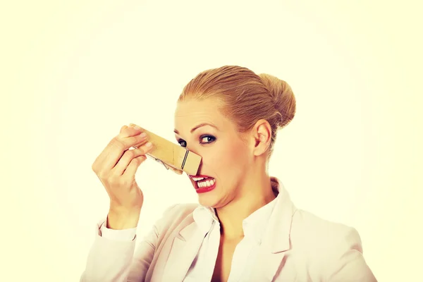 Młody biznes kobieta z ogromnym clothespin na nos. Koncepcja śmierdzi — Zdjęcie stockowe