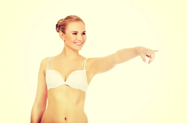 Young woman in white bra pointing for copyspace or something — Stock Photo, Image