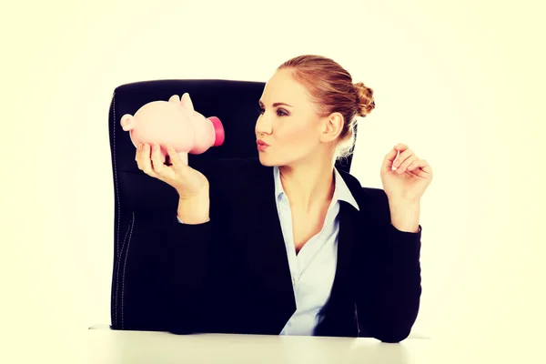 Happy business woman with a piggybank behind the desk — Stock Photo, Image