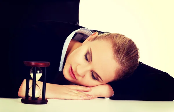 Junge Geschäftsfrau schläft auf dem Schreibtisch mit Sanduhr — Stockfoto