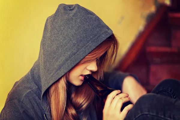 Teenage depressed woman sitting on the staircase and drinking a beer — Stock Photo, Image