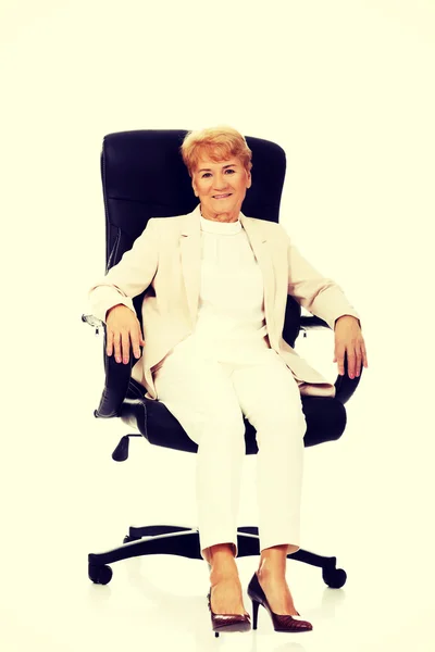 Smile elderly business woman sitting on armchair — Stock Photo, Image