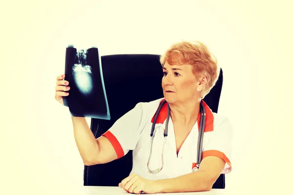 Médica idosa pensiva à procura de foto de raios-x — Fotografia de Stock