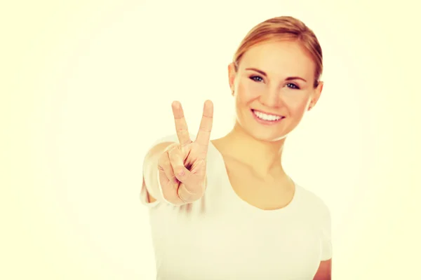 Jeune femme souriante montrant le signe de la victoire — Photo