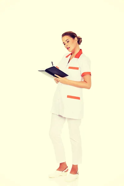 Genç kadın doktor odaklanmak veya hemşire notları yapar — Stok fotoğraf