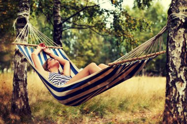 Genç sarışın kadın hamakta dinleniyor.