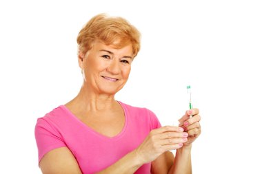 Diş macunu ve diş fırçası tutan gülümseyen kadın kıdemli