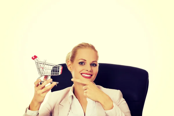 Sourire femme d'affaires assis derrière le bureau et tenant petit panier — Photo