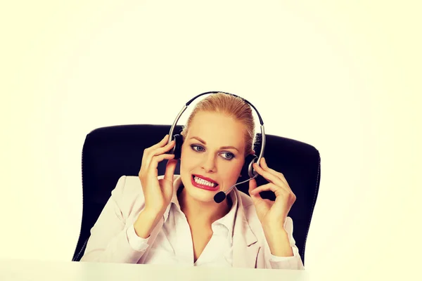 Mujer joven operador de línea de ayuda está tratando de escuchar algo a través de unos auriculares —  Fotos de Stock