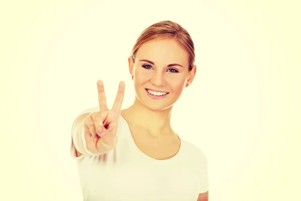 Jeune femme souriante montrant le signe de la victoire — Photo